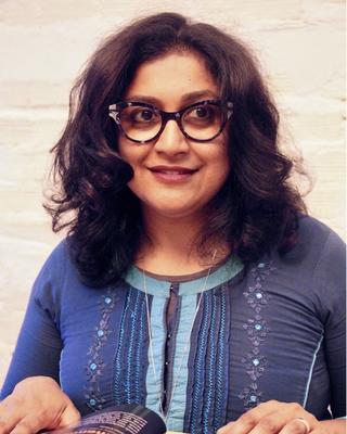 Anooradha Iyer Siddiqi looking up from a magazine or book of photographs